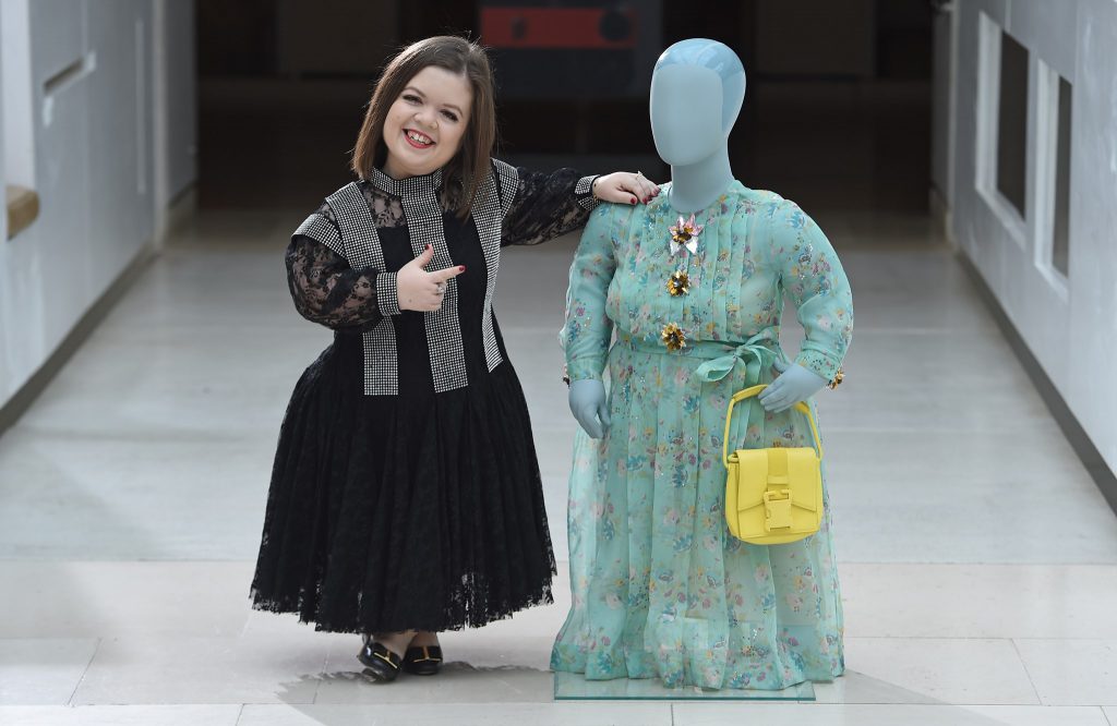 L'activiste Sinéad Burke pose à côté du premier mannequin "little person" réalisé en 2018 partir de ses dimensions. Le mannequin porte une rob et un sac à main de Christopher Kane, adaptés à partir des modèles de la collection Printemps-Eté 2018.